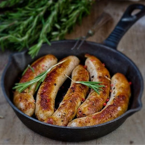 Five moose sausages in a black pan with rosemary